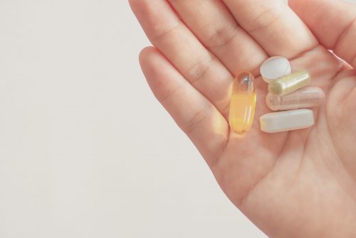 Top view of alternative organic medicine or herbal viatmin supplement capsule tablet on woman hand with copyspace background. Concept of healthy eating lifestyle.